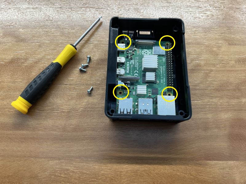 Image showing raspberry Pi in it's case with 4 screws and a screwdriver